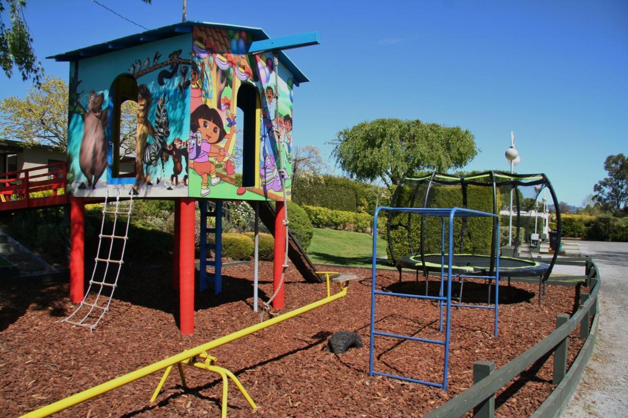 Taupo Debretts Spa Resort Екстериор снимка The photo shows a colorful playground structure that resembles a small house. It features a mural with animated characters on one side, likely including familiar children's figures. The house has ladders for climbing and a slide. Nearby, there is a c