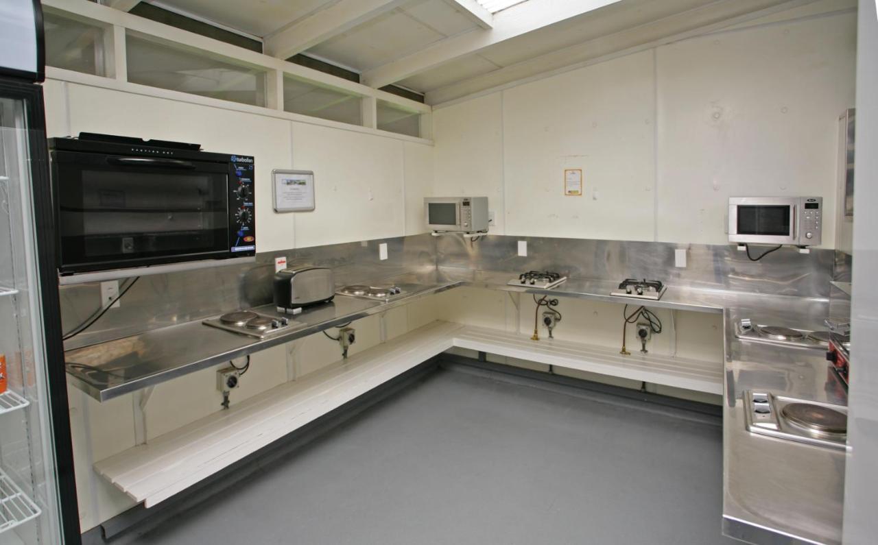 Taupo Debretts Spa Resort Екстериор снимка The photo shows a kitchen space that features stainless steel countertops and appliances. There is a wall-mounted microwave and another microwave placed on the counter. The kitchen is equipped with several gas burners and sinks. The floor has a smoot